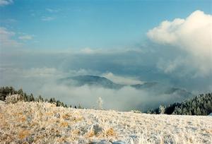 Frost covered grass on hill low clouds