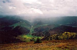 View from high hill of valley mountains and rainy/stormy clouds with sun beams