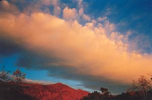 Orange cloud on blue sky, red mountains