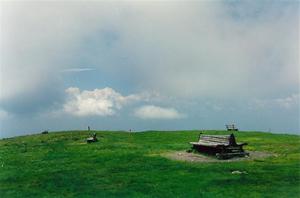 Empty benches on top of green hill, clouds