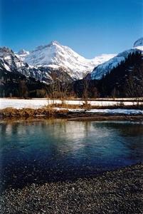 Snowy mountains with reflection on blue stream