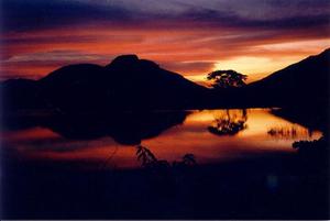 Intense red and purple sunset  and hill with reflection