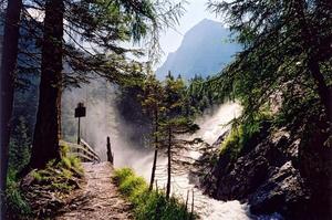 Path towards bridge and torrent below blue peak